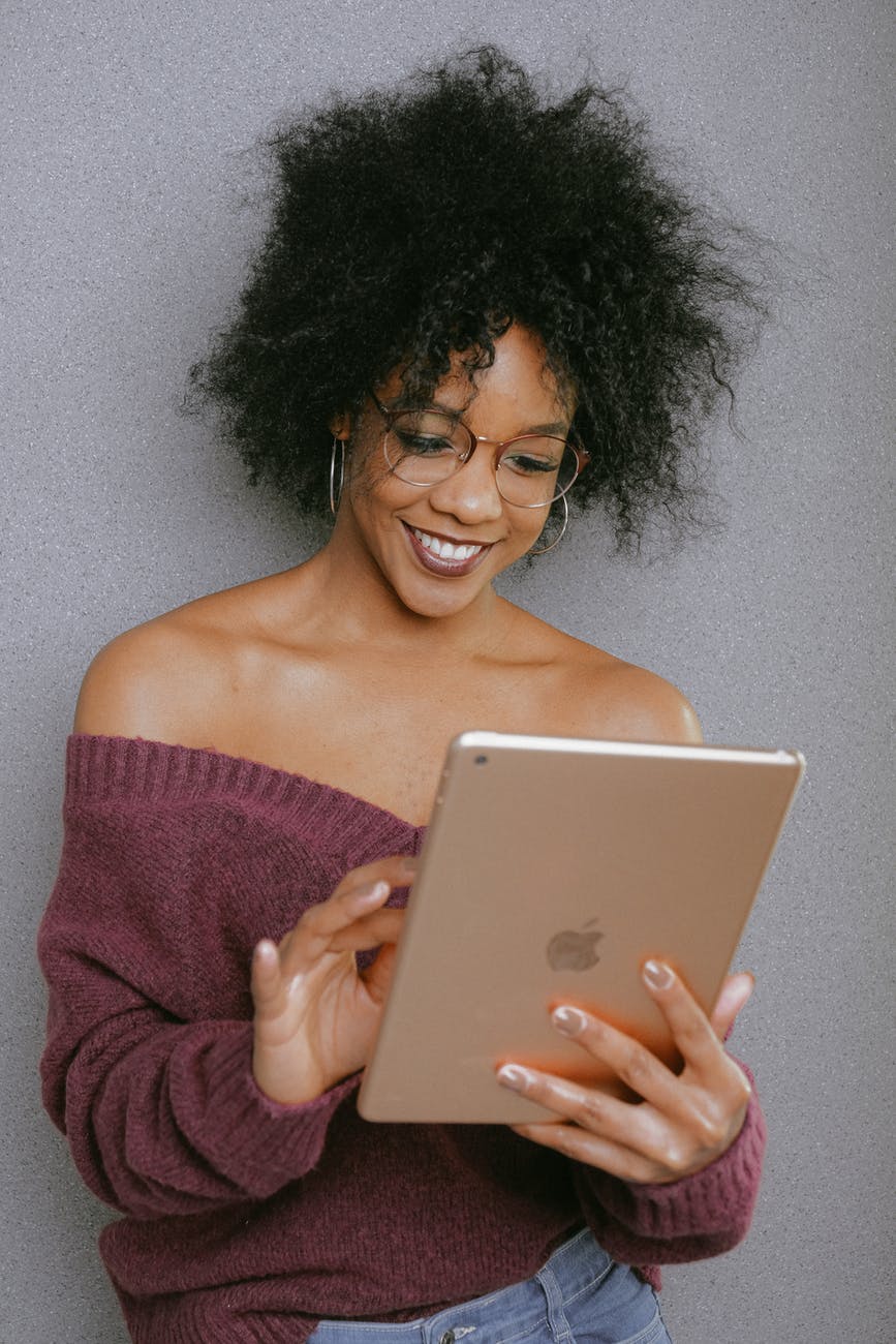 woman in purple off shoulder top holding an ipad
